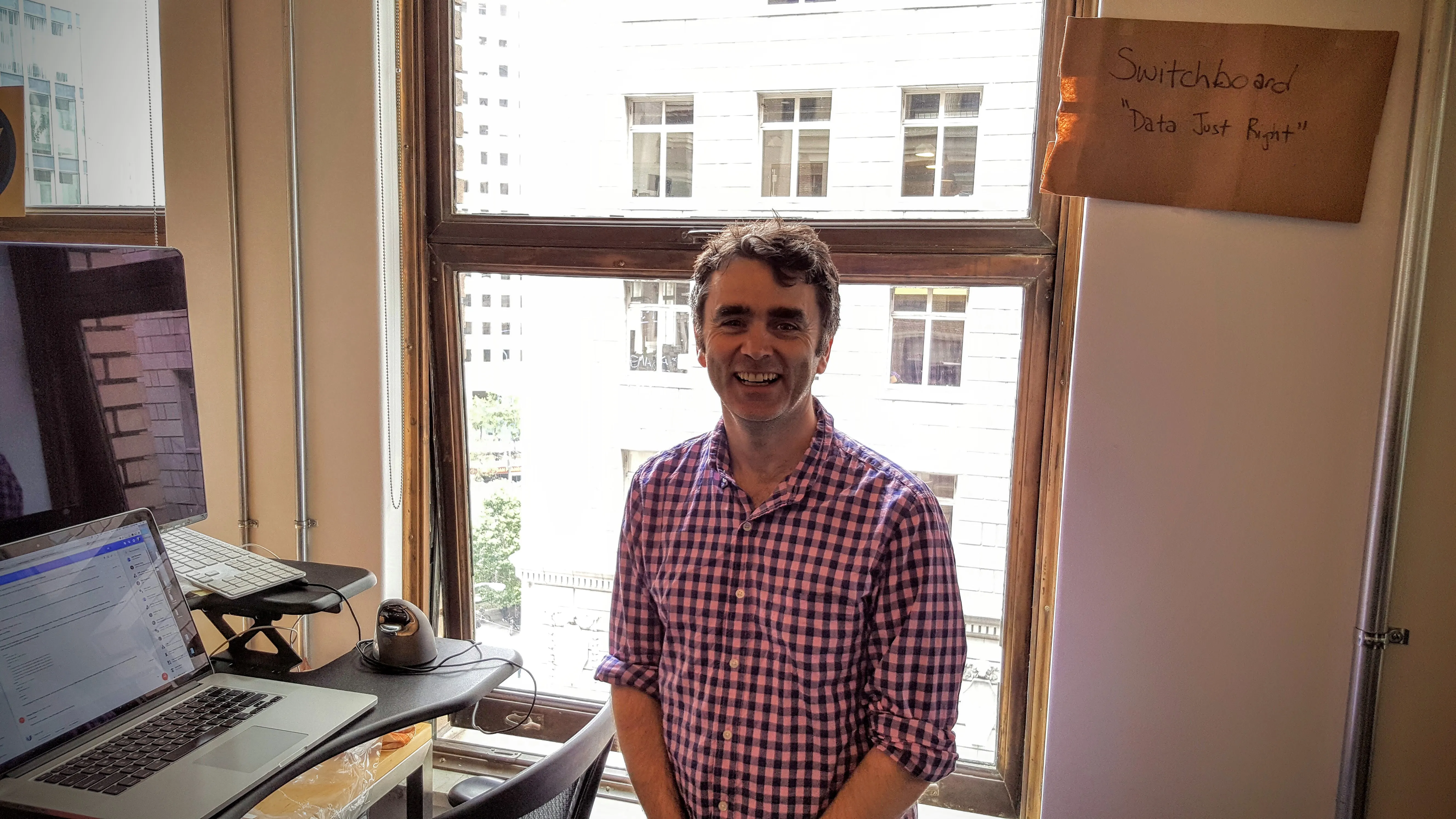 Gene at Switchboard Software office in San Francisco with standing desk and Data Just Right sign